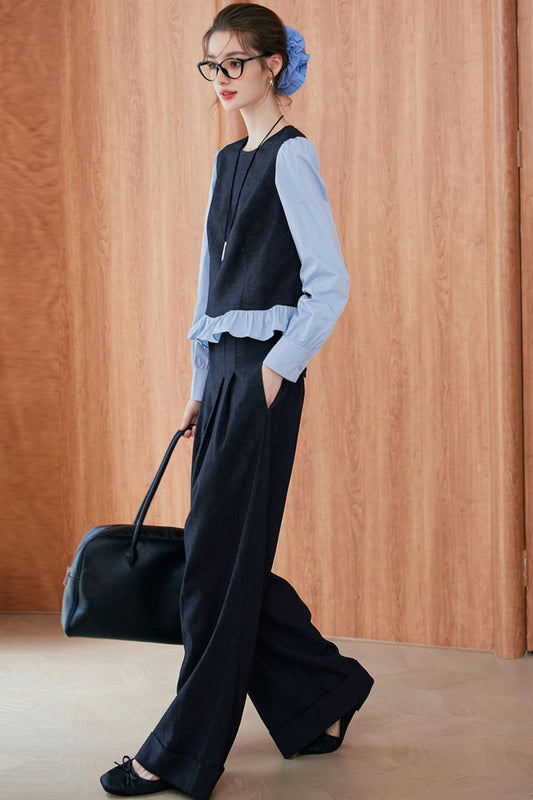 Side view of model in navy blue vest and trousers over light blue blouse with ruffled hem