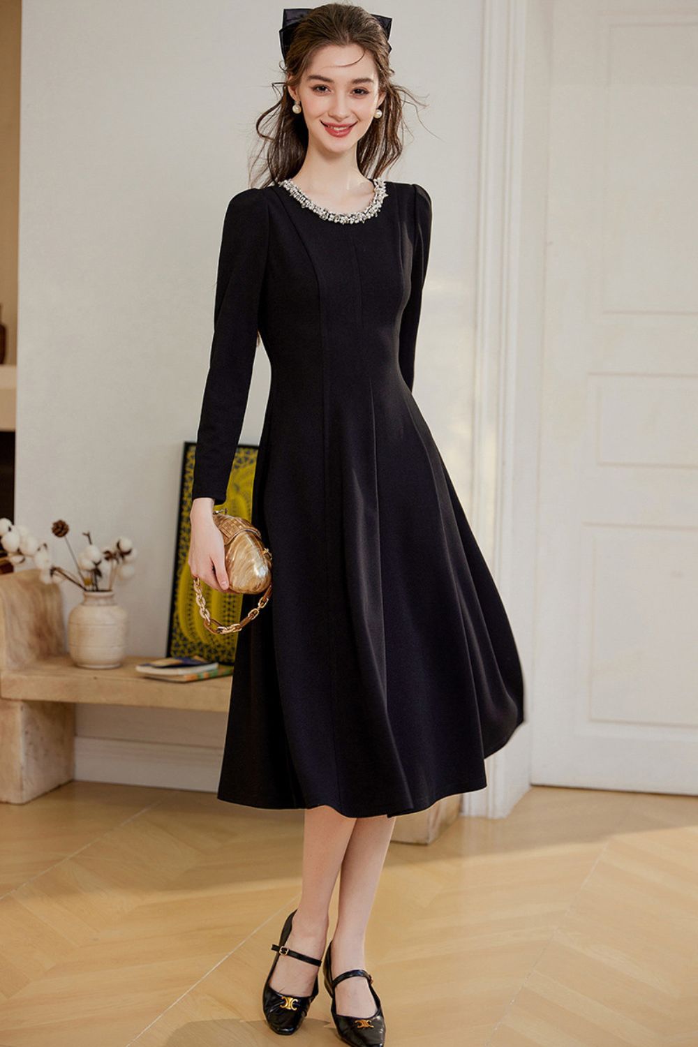 Full body view of model wearing black midi dress with black heels