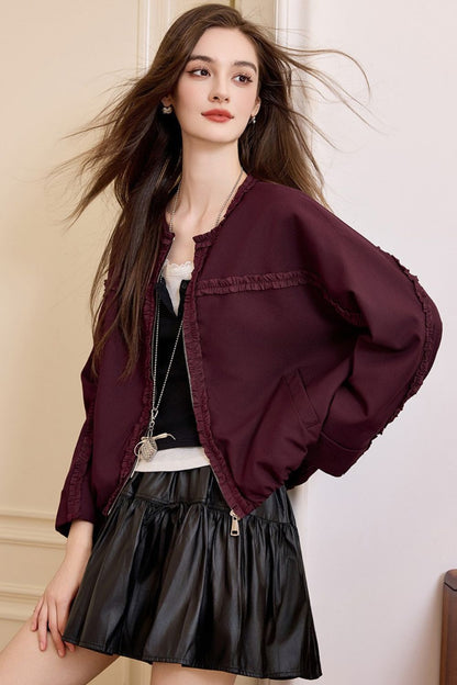 Front view of woman wearing a burgundy jacket with black pleated skirt