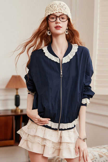 Model wearing a navy blouse with lace-trimmed collar, paired with a tiered beige mini skirt and crochet hat