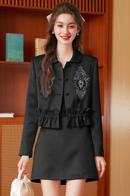 Model wearing a black embroidered jacket with tassel details paired with a black mini skirt
