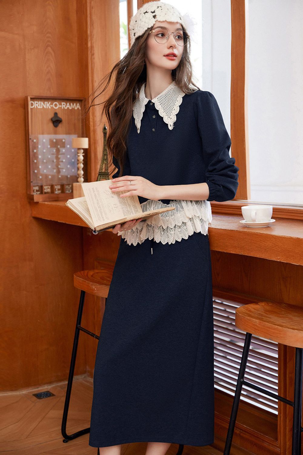 Model wearing a navy blue long-sleeve top with lace-trimmed collar and hem, paired with a navy maxi skirt and crochet hat