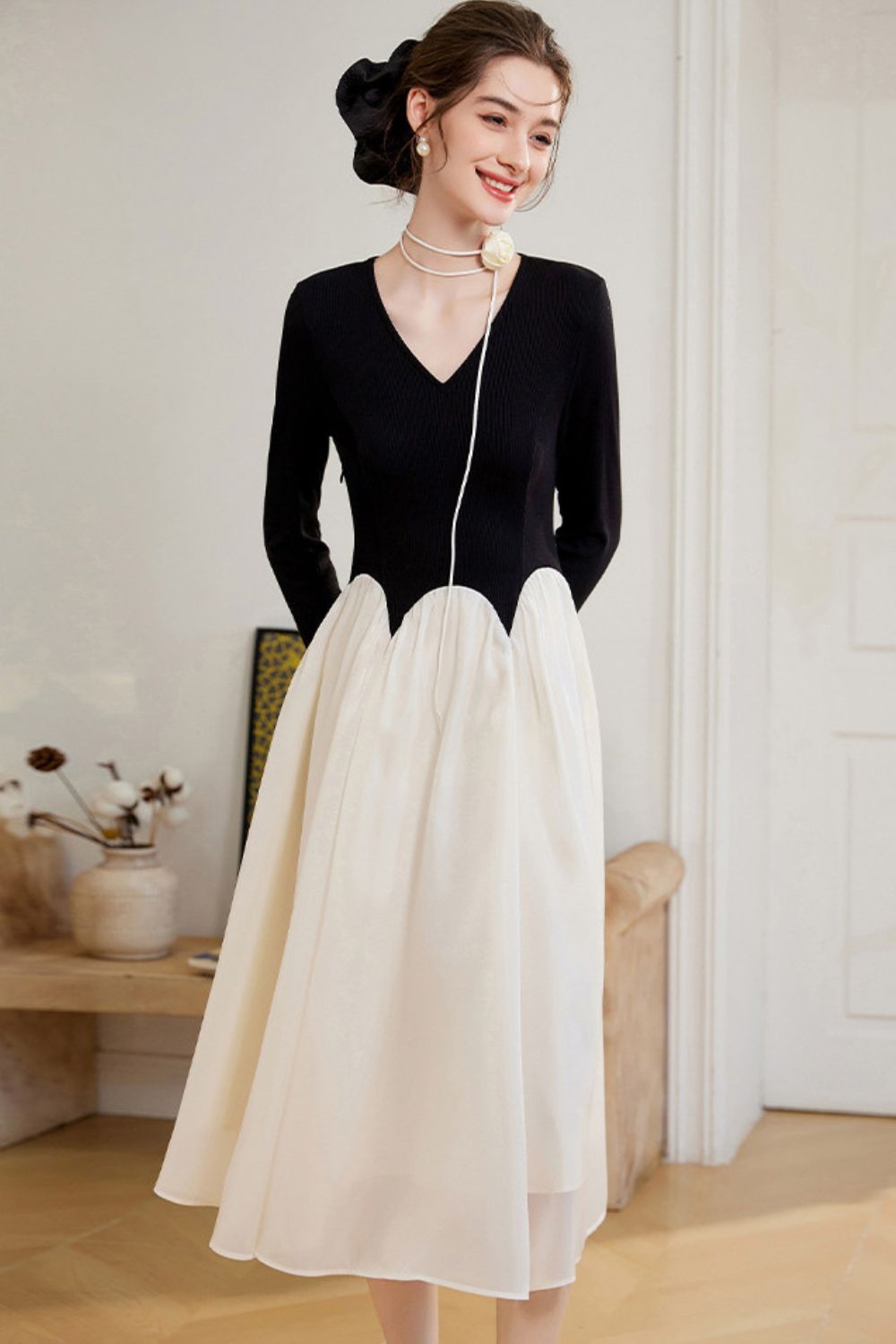 Angled view of black long-sleeve top paired with white A-line skirt