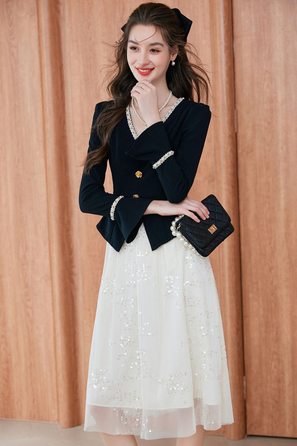 Front view of embroidered white dress layered with black buttoned blazer