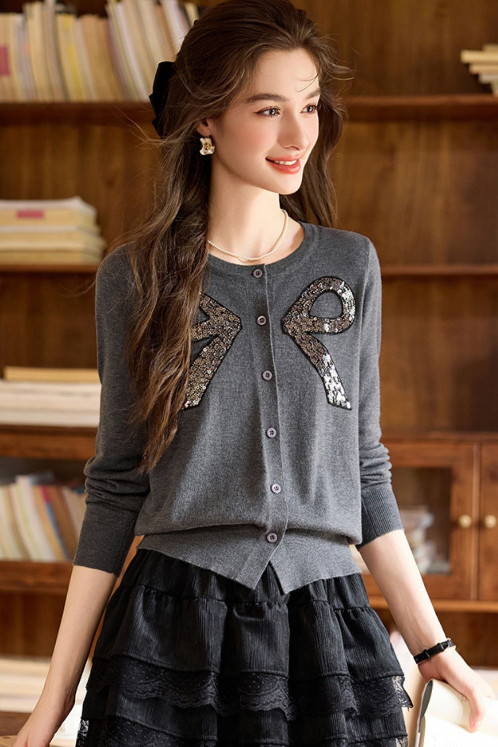 Model posing in gray bow-detailed sweater and black ruffle skirt