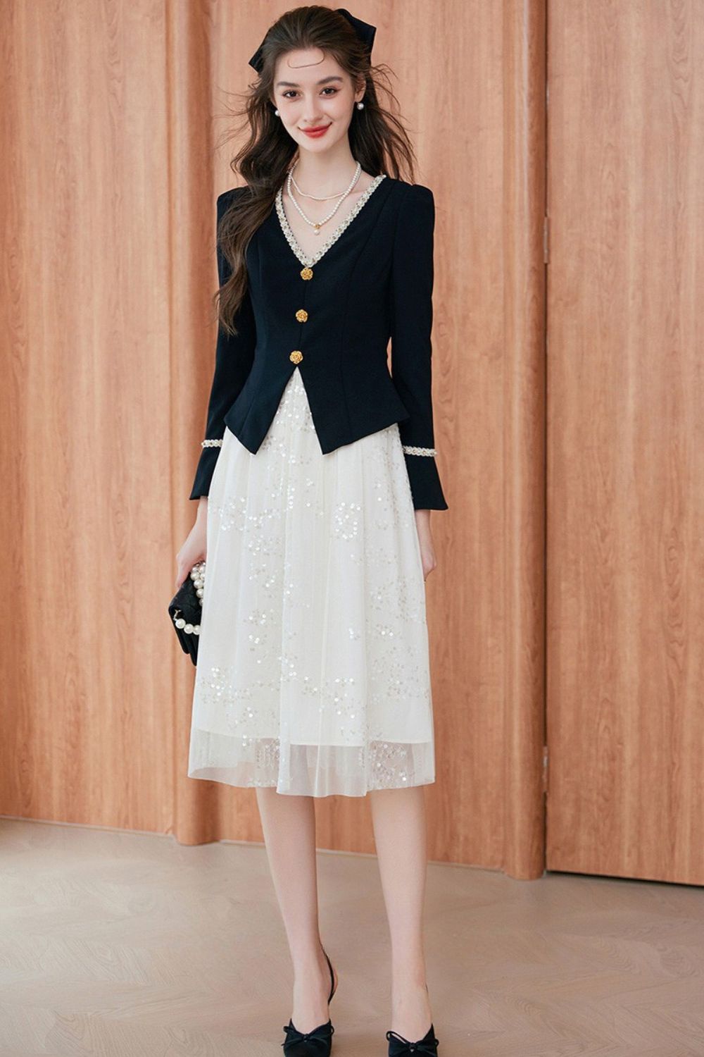 Standing pose showing black blazer with tailored hemline over white midi dress