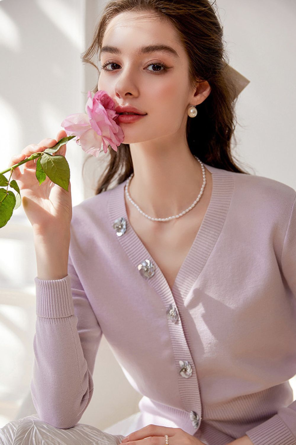 Close-up of light purple cardigan with pearl buttons styled with a white skirt