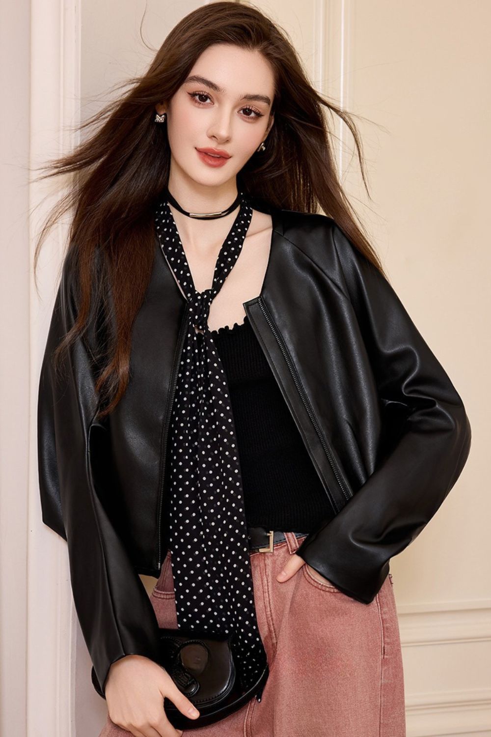 Full front view of black faux leather jacket styled with pink pants