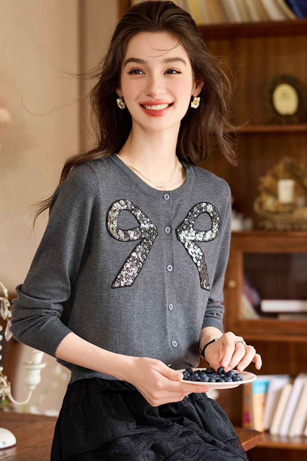 Gray embellished sweater with bow details styled with a black skirt