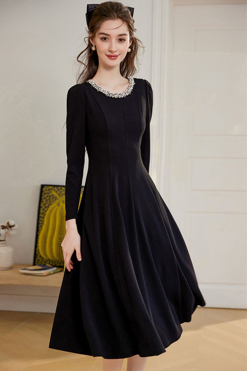 Side view of long-sleeve black midi dress with flared hem