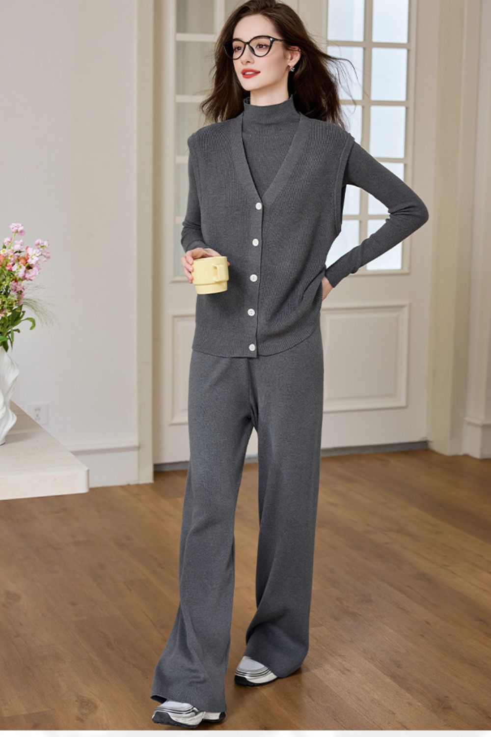 Model in a dark gray knit lounge set with long-sleeve top and wide-leg pants, posing indoors
