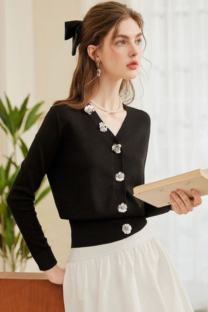 Front view of black buttoned cardigan with pearl details and white skirt