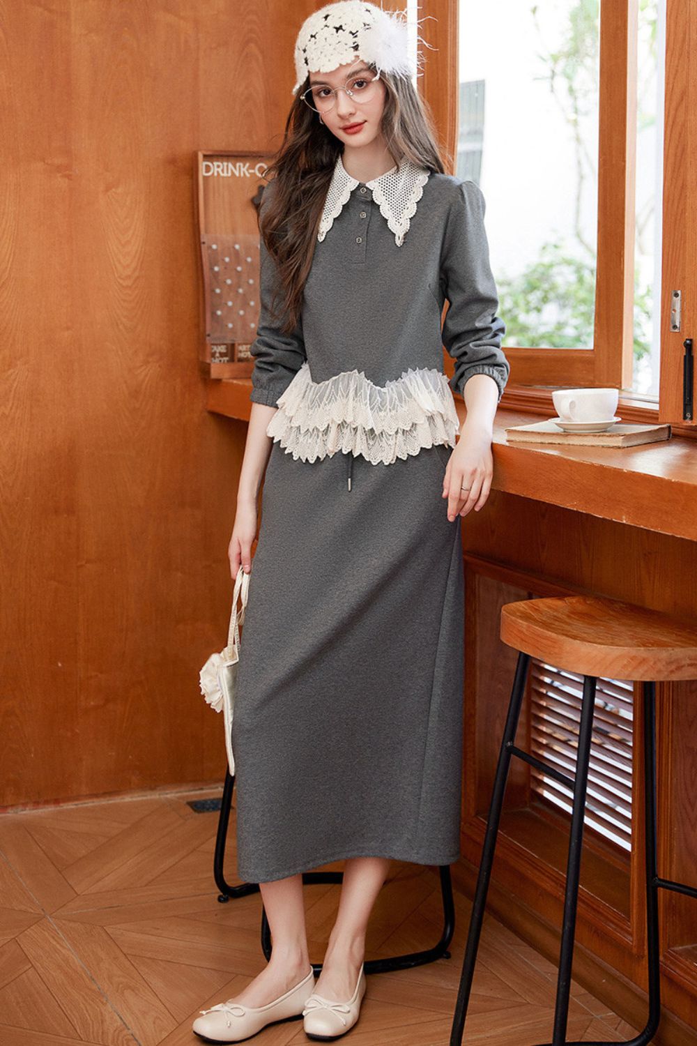 Model in gray lace-trimmed top with matching gray maxi skirt and crochet hat, standing indoors