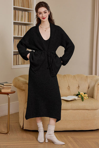 Full body view of black long knit cardigan dress styled with boots