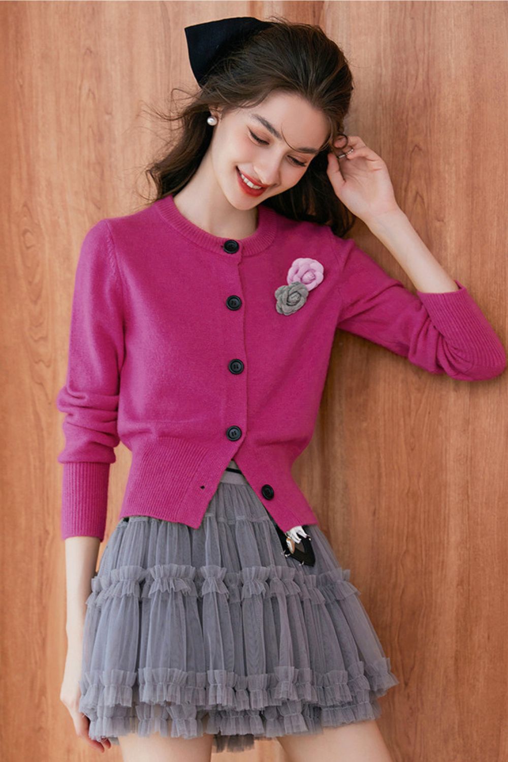 Front view of pink cardigan with brooch, paired with pleated skirt