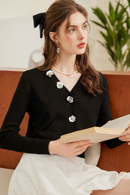 Close-up of black cardigan with pearl buttons, paired with a white skirt