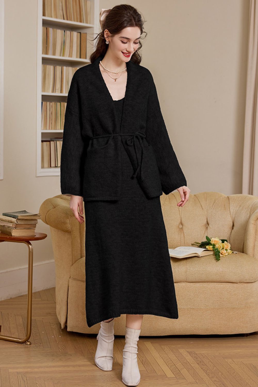 Front view of woman wearing a black long knit cardigan dress with waist tie